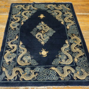 Dark blue rug with beige and slate blue dragon motifs rests on a distressed wooden floor.