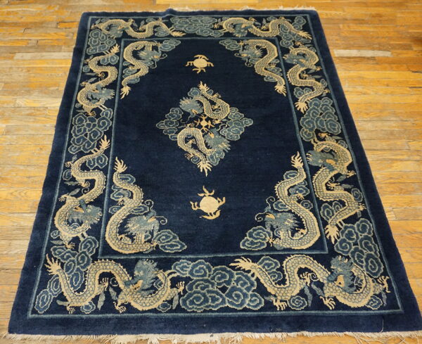 Dark blue rug with beige and slate blue dragon motifs rests on a distressed wooden floor.