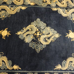 Dark blue rug displaying ornate gold and gray mythological dragons and cloud patterns forming a frame.