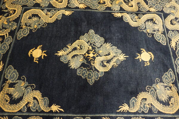Dark blue rug displaying ornate gold and gray mythological dragons and cloud patterns forming a frame.