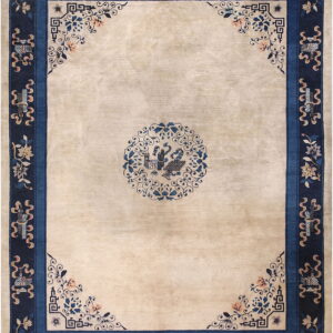 Beige rug featuring a central blue medallion and a thick navy border with floral and geometric patterns.