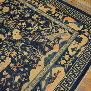 Dark blue rug with tan and coral motifs of foliage and creatures, framed by a fret border.