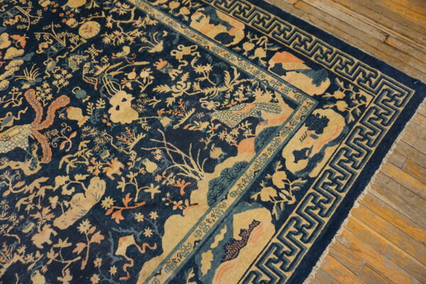 Dark blue rug with tan and coral motifs of foliage and creatures, framed by a fret border.