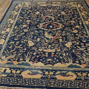 Large dark blue rug with intricate tan and peach traditional patterns on natural wood flooring.