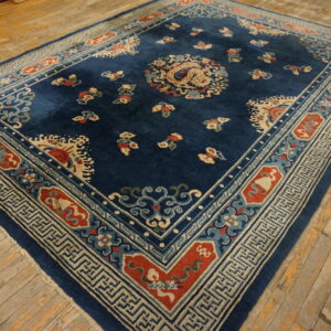 Deep blue rug with a central dragon motif and detailed traditional border on distressed wooden planks.