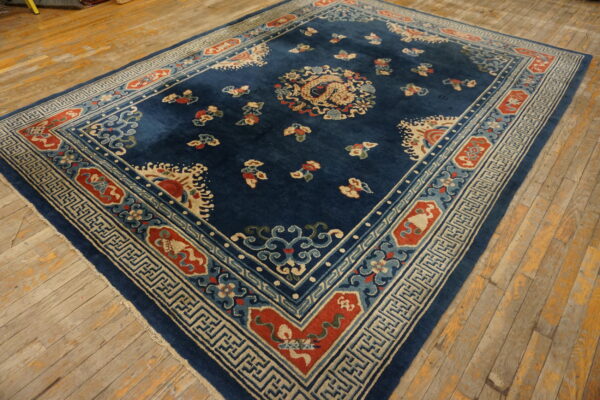 Deep blue rug with a central dragon motif and detailed traditional border on distressed wooden planks.