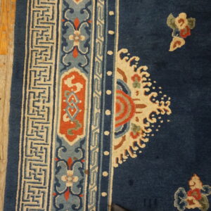 Navy rug with elaborate terracotta, light blue, and cream borders resting on distressed wooden planks.
