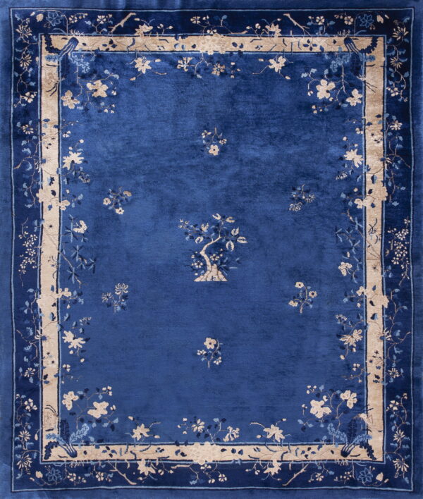 Deep blue medium-pile rug with beige floral sprigs and a thick patterned tan and blue border.