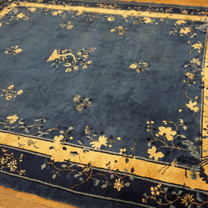 Rectangular blue rug featuring scattered yellow botanical designs and a wide, golden border on wood planks.