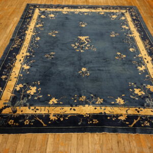 Deep blue rug with gold floral borders and scattered motifs displayed on rustic hardwood flooring.