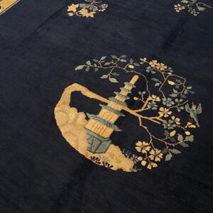 Dark blue rug with a gold and teal pagoda design surrounded by flowering branches and a border.