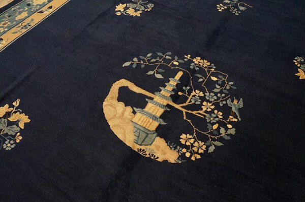Dark blue rug with a gold and teal pagoda design surrounded by flowering branches and a border.