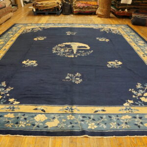 Large dark blue rug featuring a stylized yellow and light blue scenic floral pattern on wood floors.