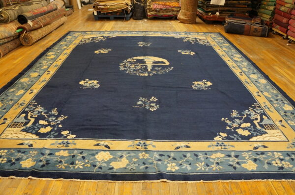 Large dark blue rug featuring a stylized yellow and light blue scenic floral pattern on wood floors.