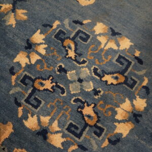 Blue pile rug detail with a central medallion pattern featuring navy and light tan motifs.