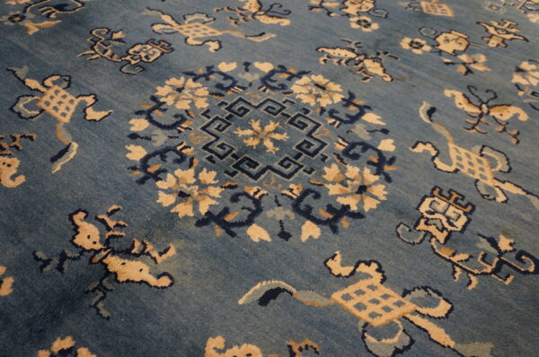 Angled view of a blue rug with a complex traditional pattern of beige, navy, and aqua motifs.