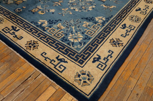 Blue and tan low-pile rug with geometric and floral patterns sits on rustic, wide-plank wood flooring.