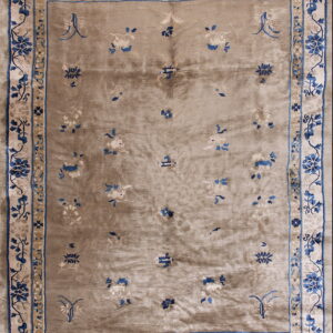 Low-pile rug with a shimmering taupe field, scattered florals, and wide blue and cream botanical borders.