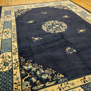 Dark blue rug with contrasting yellow and light blue floral border lies on light wooden floorboards.