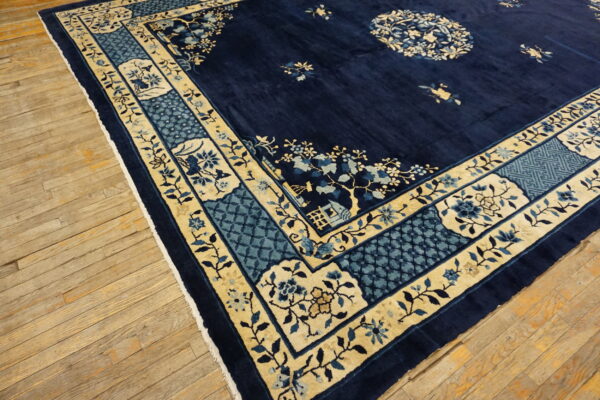 Dark blue rug with gold and light blue floral and geometric borders over distressed wood planks.