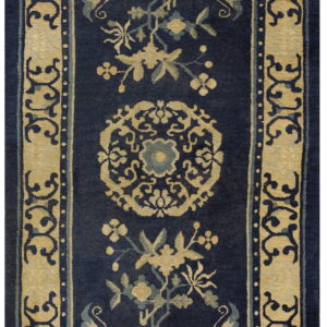 Ornate navy blue rug with beige floral patterns and a wide scroll-patterned border.