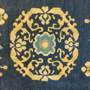 High-pile navy rug with a bright yellow scrolling medallion and pale blue floral center detail.