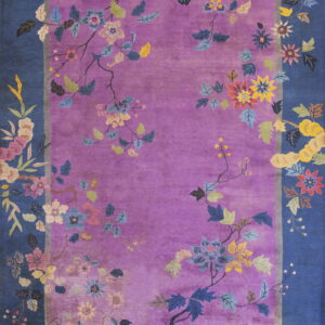 Purple rug with a blue border displays multicolored florals and vines trailing across the edges.