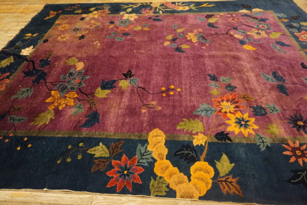 Medium pile rug with a plum field and navy border featuring a complex multi-color botanical pattern.