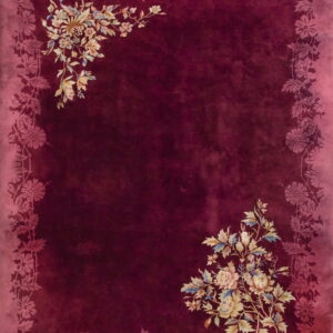 Burgundy high-pile rug with a tonal pink floral border and multicolor flower bouquets in opposite corners.