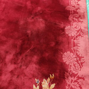 Velvety deep red rug featuring a tone-on-tone pink floral border and multicolored accent flowers.