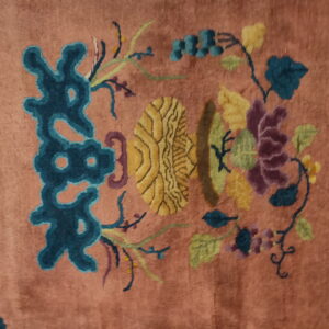 Muted pink rug detail showing stylized floral pattern in teal, bright yellow, plum, and green.