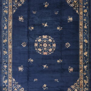 Deep blue traditional rug featuring scattered blossoms and a circular tan and blue floral medallion.