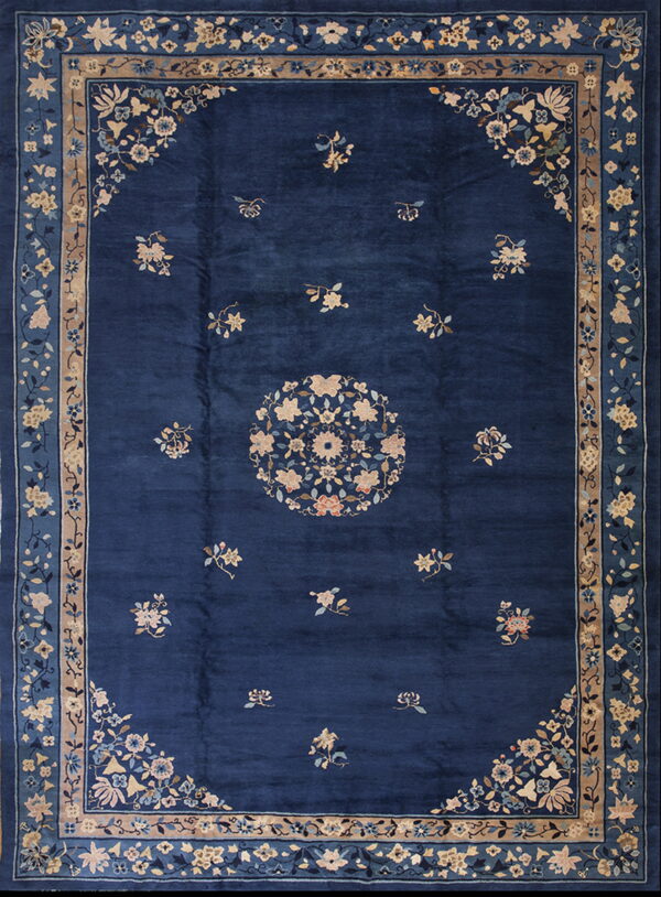 Deep blue traditional rug featuring scattered blossoms and a circular tan and blue floral medallion.