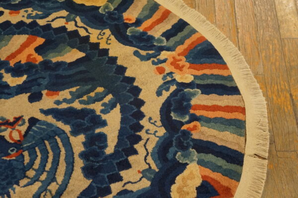 Round blue, tan, and orange patterned rug with visible fringe rests on distressed wood planks.