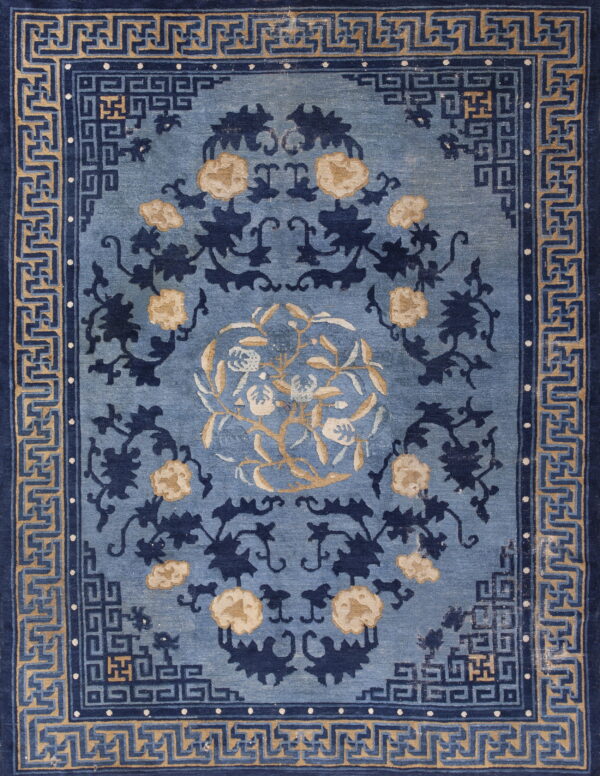 Slate blue rug with navy and tan botanical patterns bordered by complex geometric fretwork designs.