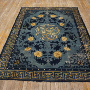 Indigo and teal rug featuring yellow floral designs and geometric borders on distressed wood floor.