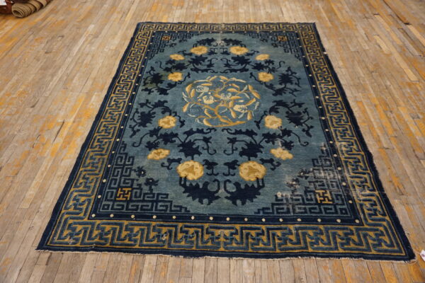 Indigo and teal rug featuring yellow floral designs and geometric borders on distressed wood floor.