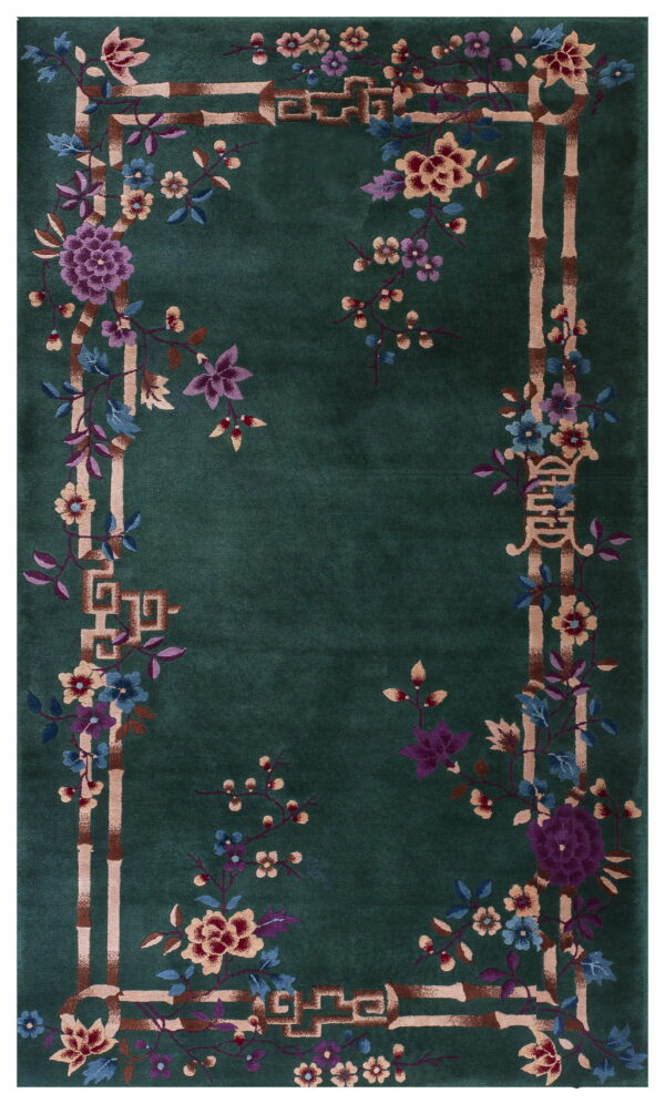 Deep green rug with a bamboo border framing multicolored flowers and stylized key patterns.