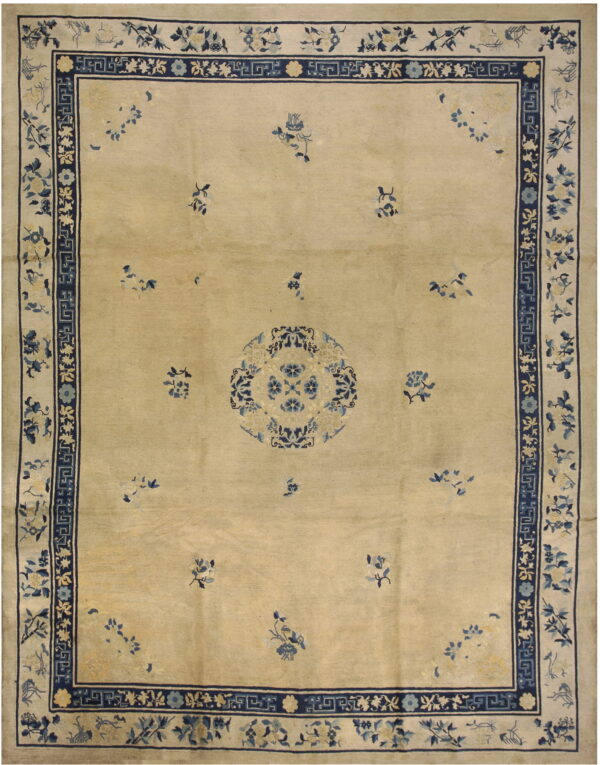 Tan low-pile rug with dark blue borders, central medallion, and scattered light blue floral designs.