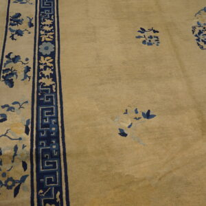 Beige rug with deep blue, light blue, and yellow floral patterns and a geometric border on wood floors.