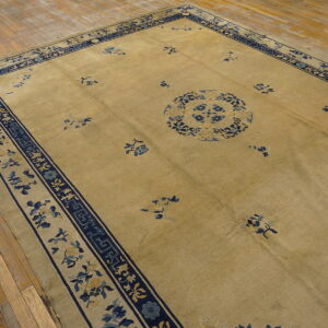 Large beige rug with a blue floral medallion and wide navy border on wood floors.