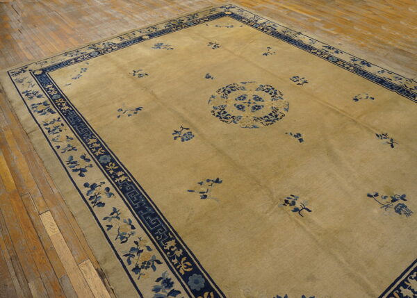 Large beige rug with a blue floral medallion and wide navy border on wood floors.