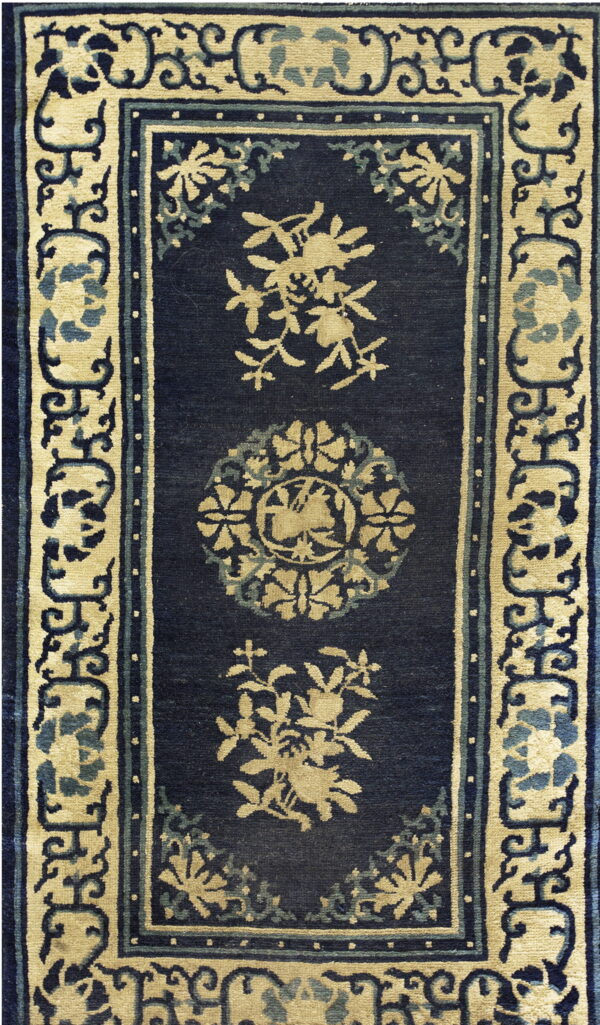 Rectangular navy blue rug with stylized beige floral motifs and a complex scrolling border design.