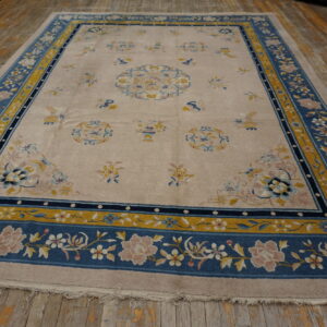 Beige rug with traditional blue and mustard yellow border, detailed with pink and white floral motifs.