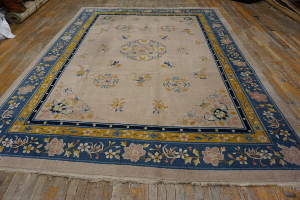 Beige rug with traditional blue and mustard yellow border, detailed with pink and white floral motifs.
