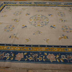 Beige rug with wide blue and gold borders, featuring floral and bird motifs in pink and yellow on a wood floor.