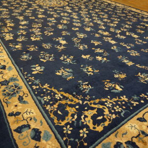 A navy blue rug featuring gold and light blue floral medallions rests on light wood plank flooring.