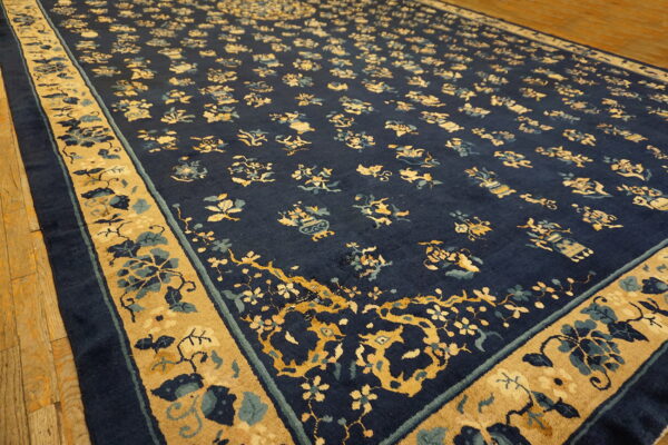 A navy blue rug featuring gold and light blue floral medallions rests on light wood plank flooring.