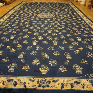 Navy blue area rug with scattered floral and vase motifs displayed on a wooden floor.