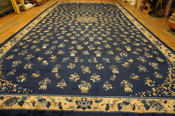 Navy blue area rug with scattered floral and vase motifs displayed on a wooden floor.